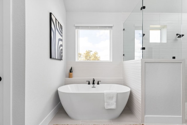 bathroom featuring baseboards, a freestanding tub, and tiled shower