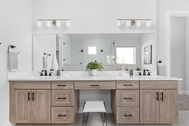 bathroom featuring double vanity, tiled shower, and a sink