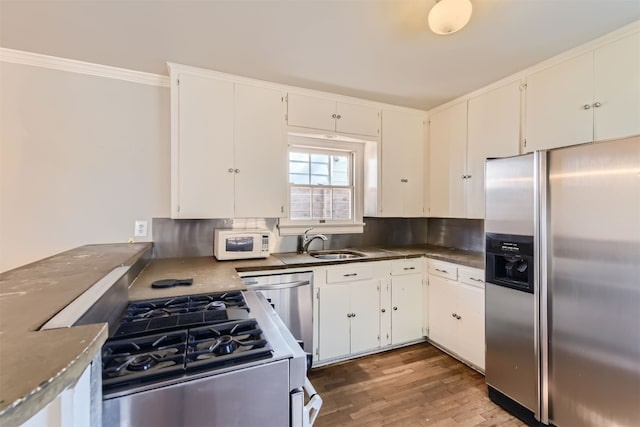 kitchen featuring stainless steel appliances, white cabinetry, hardwood / wood-style flooring, and sink