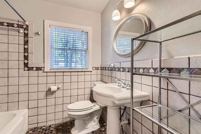 bathroom featuring tiled shower / bath, tile walls, toilet, and tile patterned floors