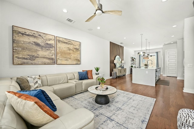 living room featuring ceiling fan, dark wood-type flooring, and sink