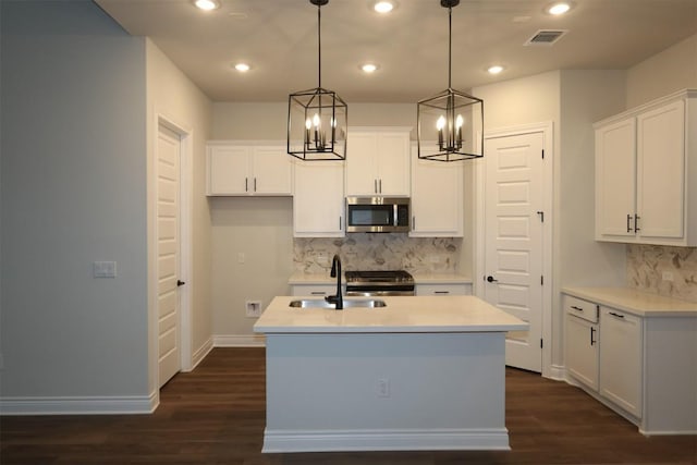 kitchen featuring sink, white cabinetry, decorative light fixtures, a center island with sink, and appliances with stainless steel finishes