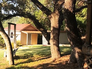 18111 Gregg Bluff Rd, Jonestown, TX 78645 - view of front of home with a storage shed, a front lawn, and stucco siding