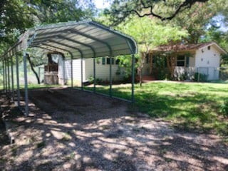 view of parking / parking lot featuring a lawn and a carport