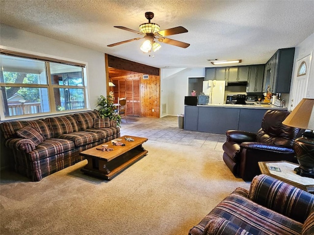 carpeted living room featuring ceiling fan, wooden walls, and a textured ceiling