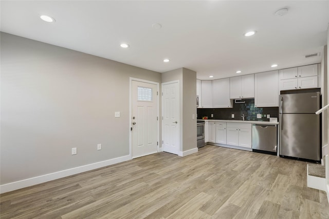 kitchen featuring white cabinetry, light hardwood / wood-style flooring, tasteful backsplash, and appliances with stainless steel finishes