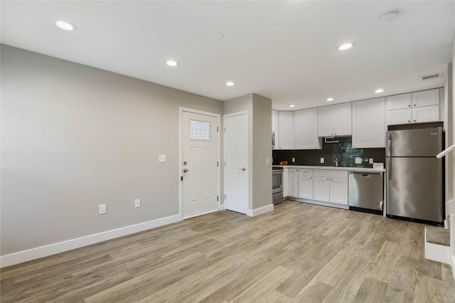 kitchen featuring white cabinetry, decorative backsplash, light hardwood / wood-style floors, and appliances with stainless steel finishes