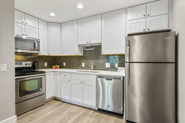 kitchen featuring sink, tasteful backsplash, light hardwood / wood-style flooring, appliances with stainless steel finishes, and white cabinets