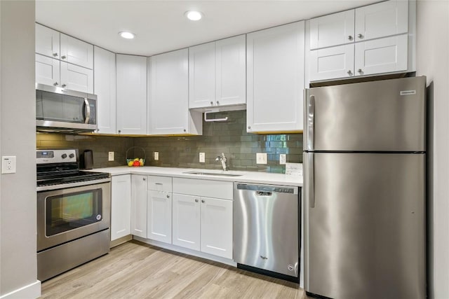 kitchen with sink, appliances with stainless steel finishes, white cabinets, and light hardwood / wood-style floors