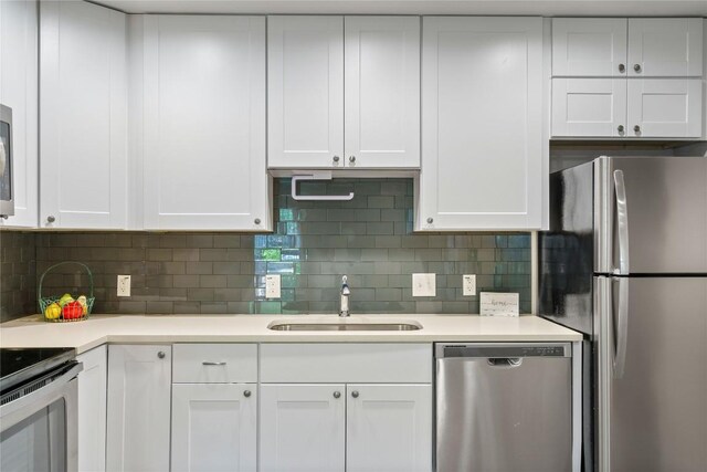 kitchen featuring tasteful backsplash, appliances with stainless steel finishes, sink, and white cabinets