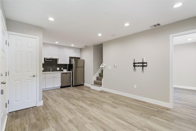 kitchen featuring visible vents, light wood-style flooring, decorative backsplash, white cabinets, and appliances with stainless steel finishes