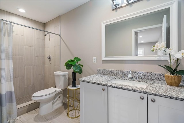 bathroom featuring a tile shower, toilet, and vanity