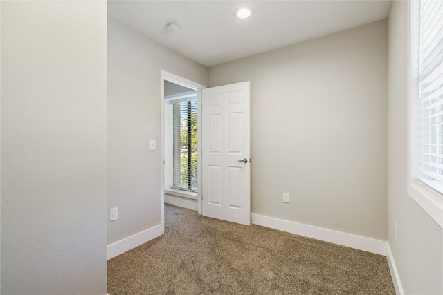 carpeted spare room featuring plenty of natural light and baseboards