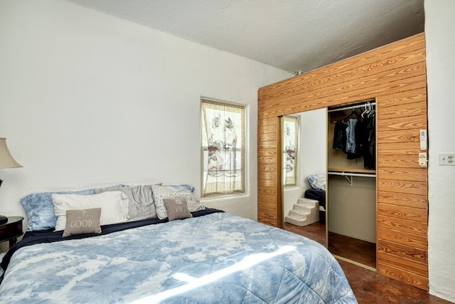 bedroom with wooden walls, a closet, and a textured ceiling