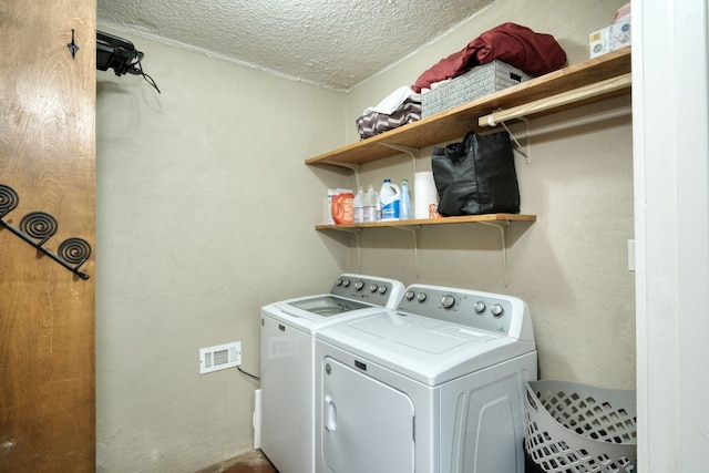 washroom with a textured ceiling and independent washer and dryer