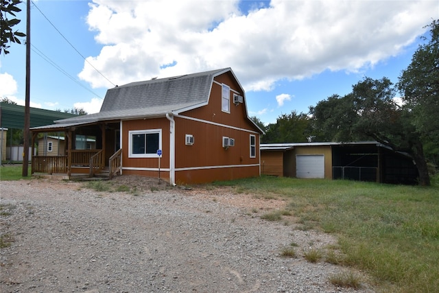 view of front facade featuring a garage, covered porch, an outdoor structure, and a wall mounted air conditioner