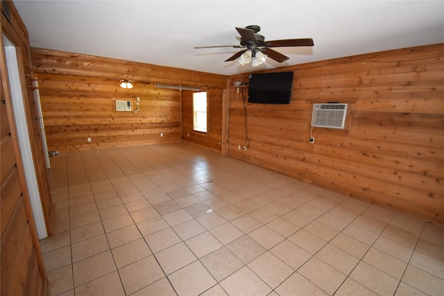 tiled empty room with ceiling fan, wood walls, a barn door, and a wall unit AC