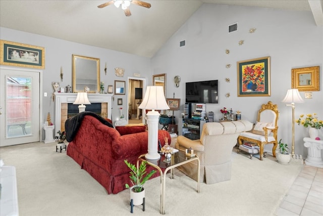 living room featuring a tile fireplace, light tile patterned floors, ceiling fan, and high vaulted ceiling