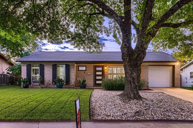 single story home featuring a garage, central AC unit, and a front yard