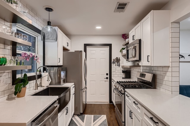 kitchen featuring white cabinets, appliances with stainless steel finishes, dark hardwood / wood-style floors, and decorative light fixtures