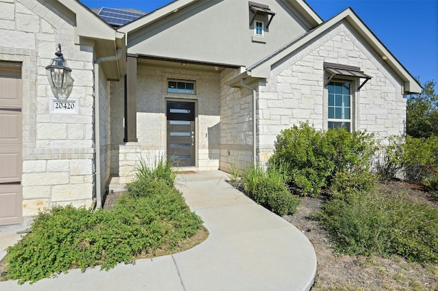 view of exterior entry with solar panels and a garage