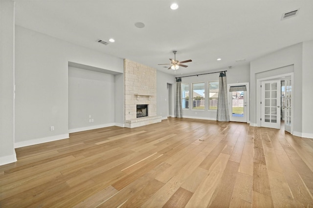 unfurnished living room featuring ceiling fan, light wood-type flooring, and a fireplace