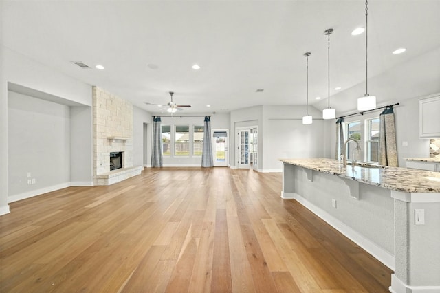 unfurnished living room featuring sink, light wood-type flooring, a wealth of natural light, and ceiling fan