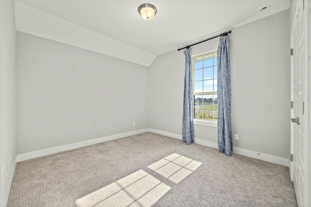 carpeted empty room featuring vaulted ceiling