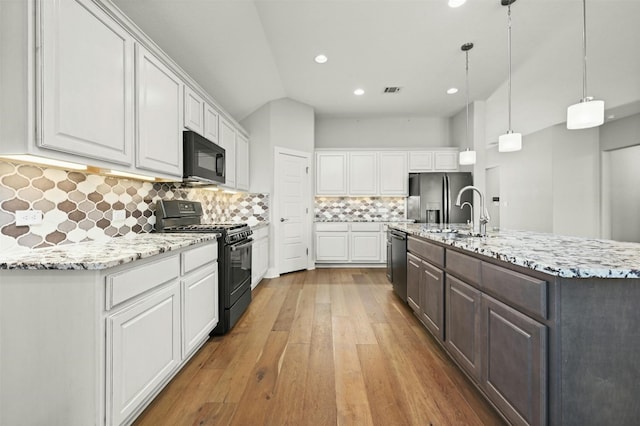 kitchen with white cabinetry, pendant lighting, black appliances, and light hardwood / wood-style flooring