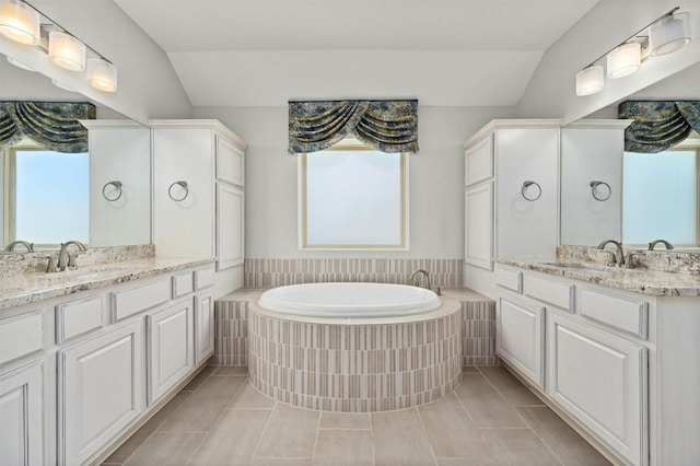 bathroom featuring tile patterned floors, tiled bath, vanity, and vaulted ceiling