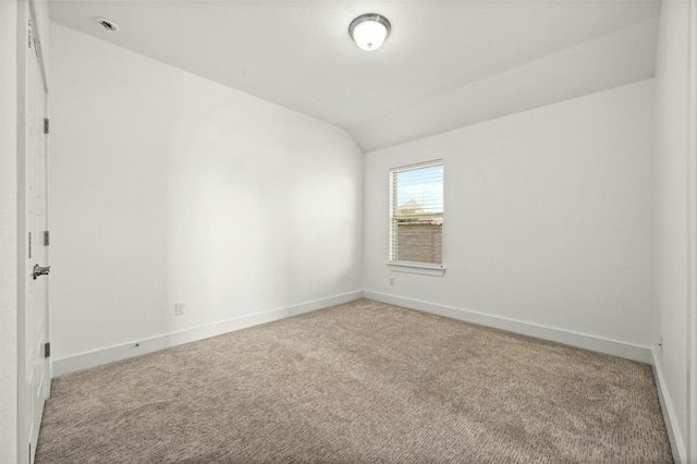 spare room with light carpet and vaulted ceiling