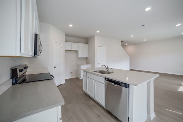 kitchen with appliances with stainless steel finishes, light wood-type flooring, sink, a center island with sink, and white cabinetry