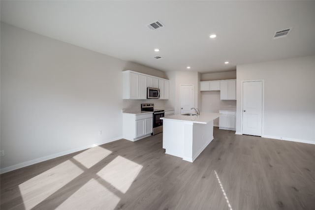 kitchen with a center island with sink, light hardwood / wood-style floors, white cabinets, and stainless steel appliances