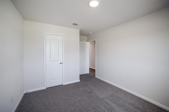 unfurnished bedroom featuring dark carpet and a closet