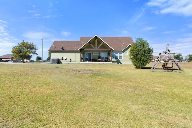 rear view of house featuring a playground and a yard