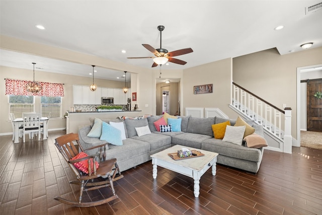 living room featuring ceiling fan with notable chandelier and dark hardwood / wood-style flooring