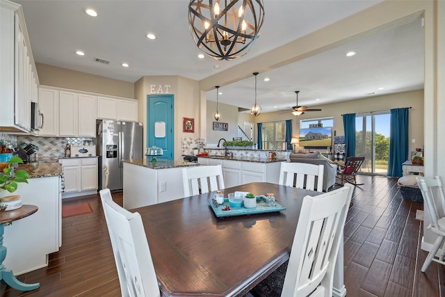 dining area with sink, ceiling fan with notable chandelier, and dark hardwood / wood-style flooring