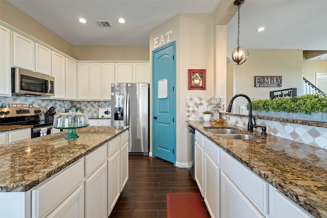 kitchen with sink, white cabinets, decorative backsplash, stainless steel appliances, and dark stone countertops