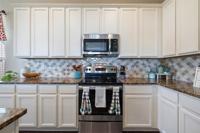 kitchen with dark stone countertops, white cabinets, appliances with stainless steel finishes, and tasteful backsplash