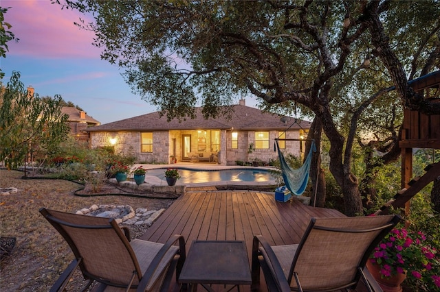 back house at dusk featuring a swimming pool side deck