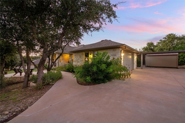 view of front of house with a garage, concrete driveway, and stone siding