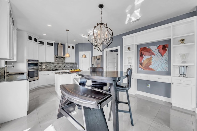 kitchen with a center island, sink, white cabinets, wall chimney range hood, and stainless steel appliances