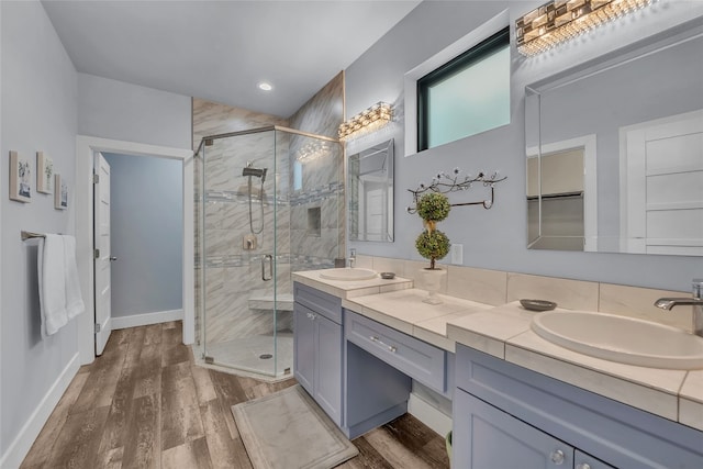 bathroom featuring hardwood / wood-style floors, a shower with door, and vanity