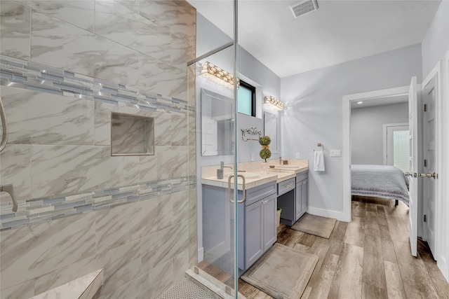 bathroom featuring a healthy amount of sunlight, a tile shower, vanity, and hardwood / wood-style flooring