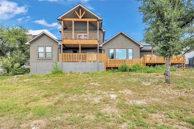 rear view of property featuring a wooden deck and a lawn