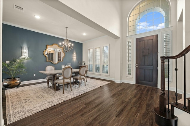 entrance foyer with ornamental molding, dark hardwood / wood-style floors, a towering ceiling, and a notable chandelier