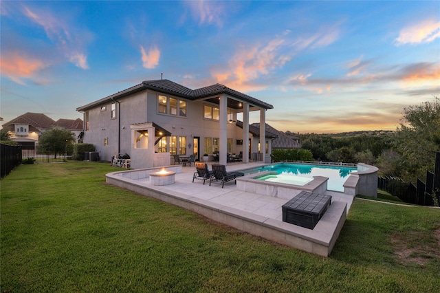 back house at dusk with a swimming pool with hot tub, a yard, and a patio