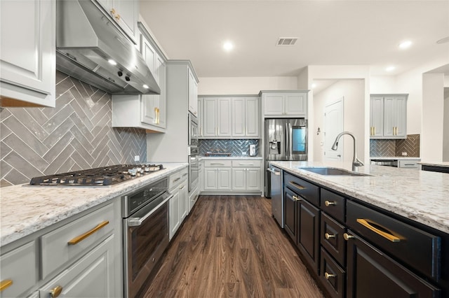 kitchen featuring decorative backsplash, light stone countertops, stainless steel appliances, dark hardwood / wood-style floors, and sink