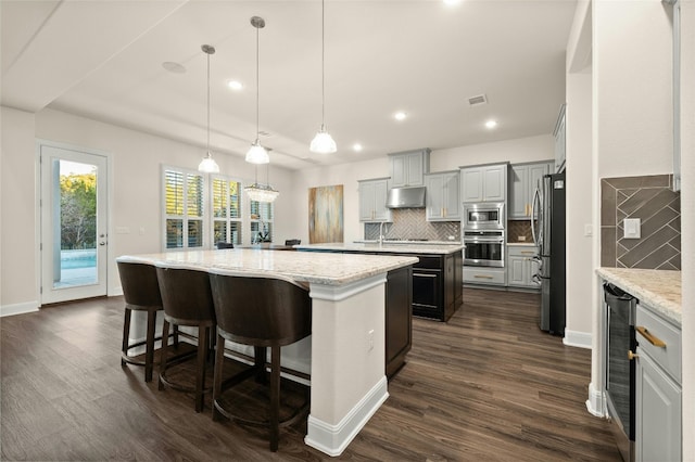 kitchen featuring pendant lighting, gray cabinetry, dark wood-type flooring, stainless steel appliances, and a center island