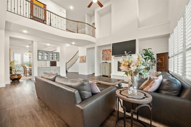 living room featuring hardwood / wood-style flooring, ceiling fan with notable chandelier, and a high ceiling